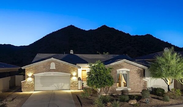 A two-story house with a stone facade, a garage, and a well-maintained front yard with landscaping. - South by Southwest - Signature Vacation Rentals (Scottsdale)