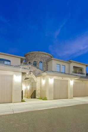 A modern multi-story house with a stone tower, multiple garages, and a covered driveway. - Sonoran Sunset By Signature Vacation Rentals (Phoenix)
