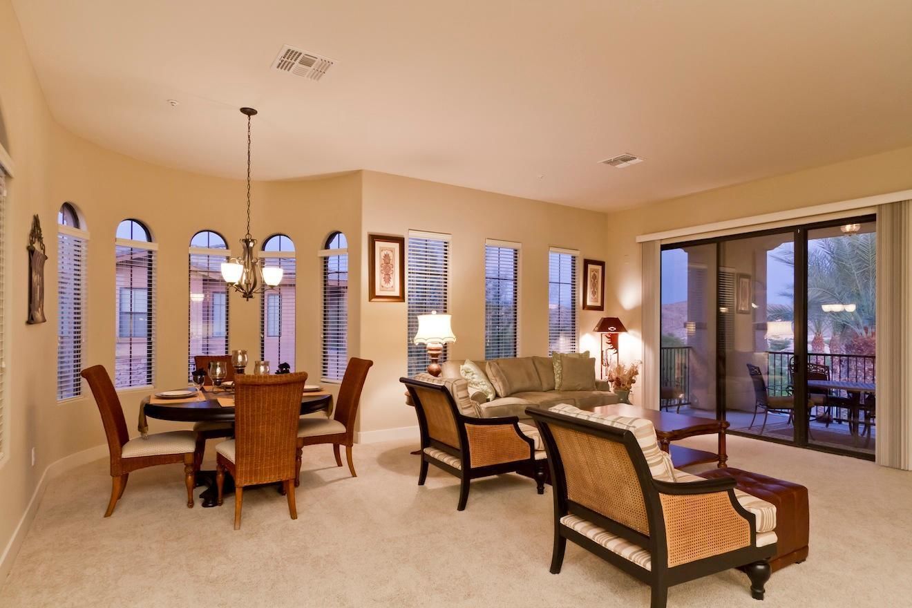 A spacious living room with a dining area, large windows, and a balcony with outdoor furniture.