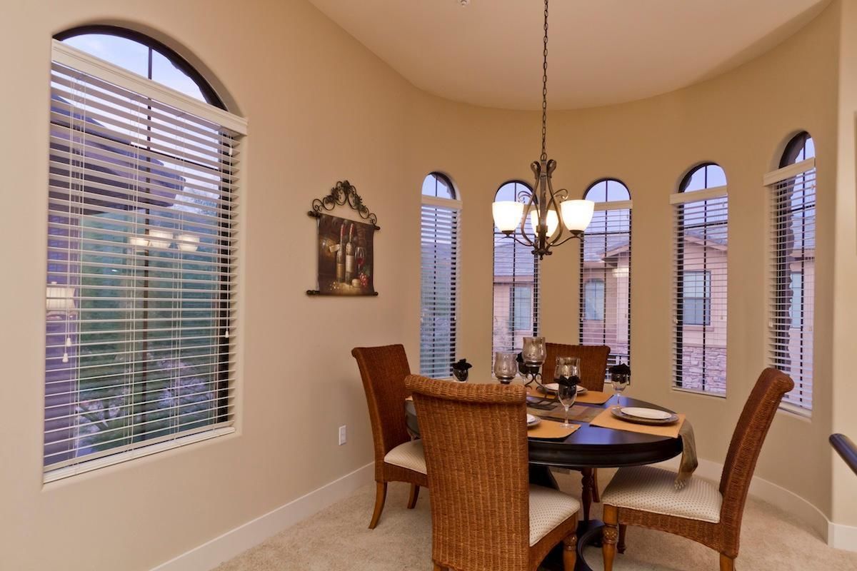 A dining room with a round table, wicker chairs, and a chandelier.