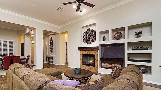 A living room with a fireplace, sofas, a TV, and shelves with decorative items.