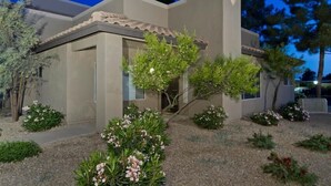 Ein modernes Gebäude mit flachem Dach, großen Fenstern und einem kleinen Gartenbereich mit verschiedenen Pflanzen und Blumen.