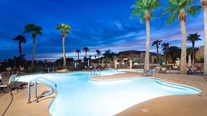 Une piscine avec des chaises longues et des palmiers.