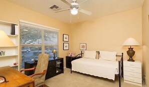 A bedroom with a bed, a desk, a chair, a nightstand, a lamp, and a ceiling fan. - Solera Primo By Signature Vacation Rentals (Chandler)
