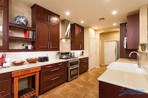 A modern kitchen with wooden cabinets, a stainless steel range hood, and a white countertop.