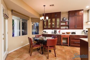 A kitchen with wooden cabinets, a dining table with chairs, and a chandelier.