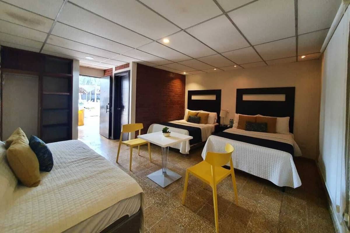 Une chambre d’hôtel avec deux lits, une petite table et deux chaises.