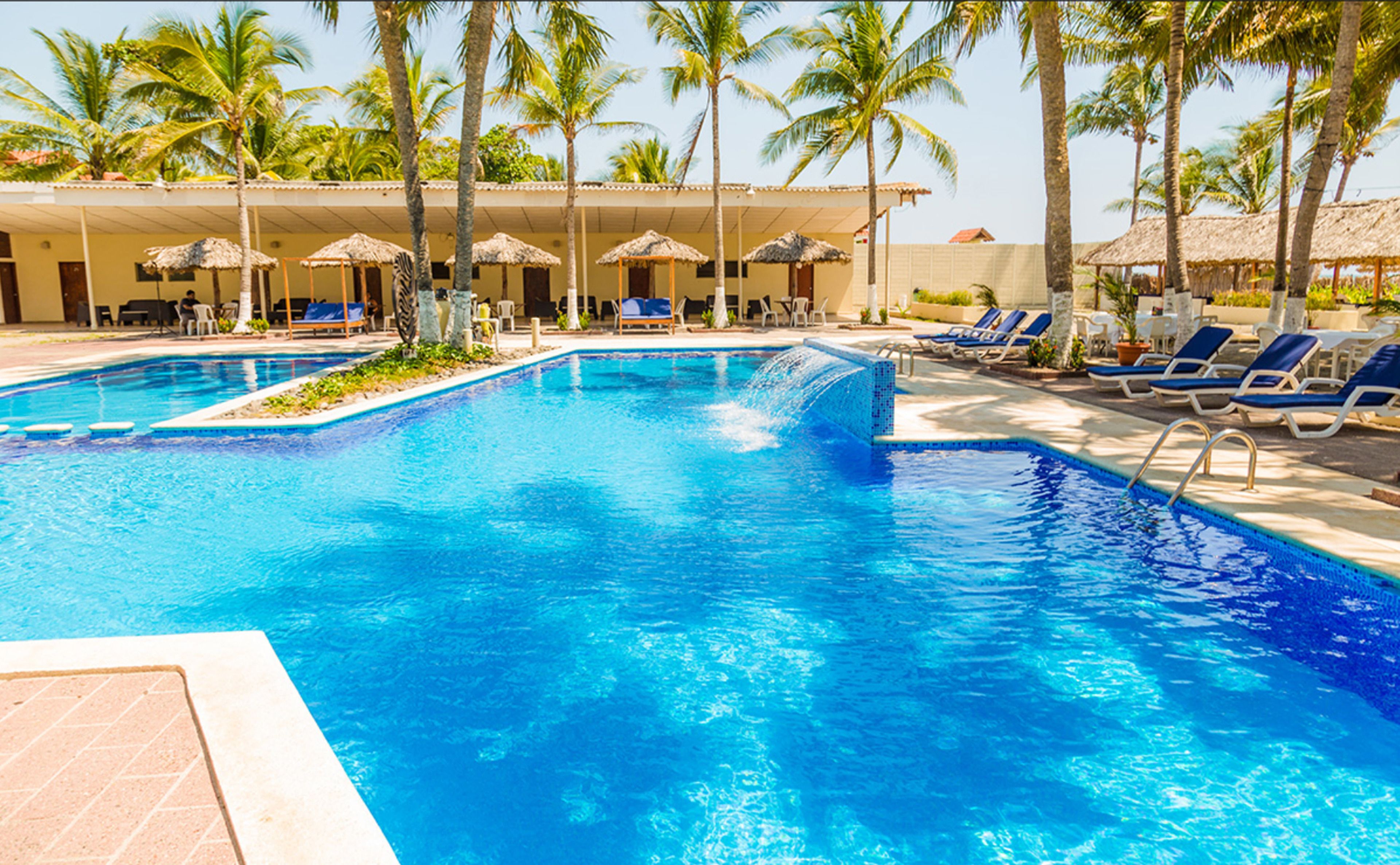Ein Pool mit Liegestühlen und Palmen.