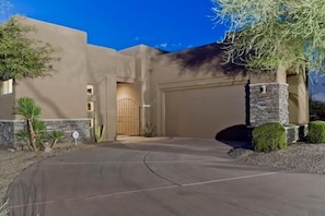 A modern house with a garage, a driveway, and landscaping.