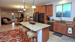 A modern kitchen with granite countertops, wooden cabinets, and a large island with bar stools.