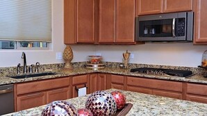 A kitchen with granite countertops, wooden cabinets, a stainless steel sink, a microwave, and a stove.