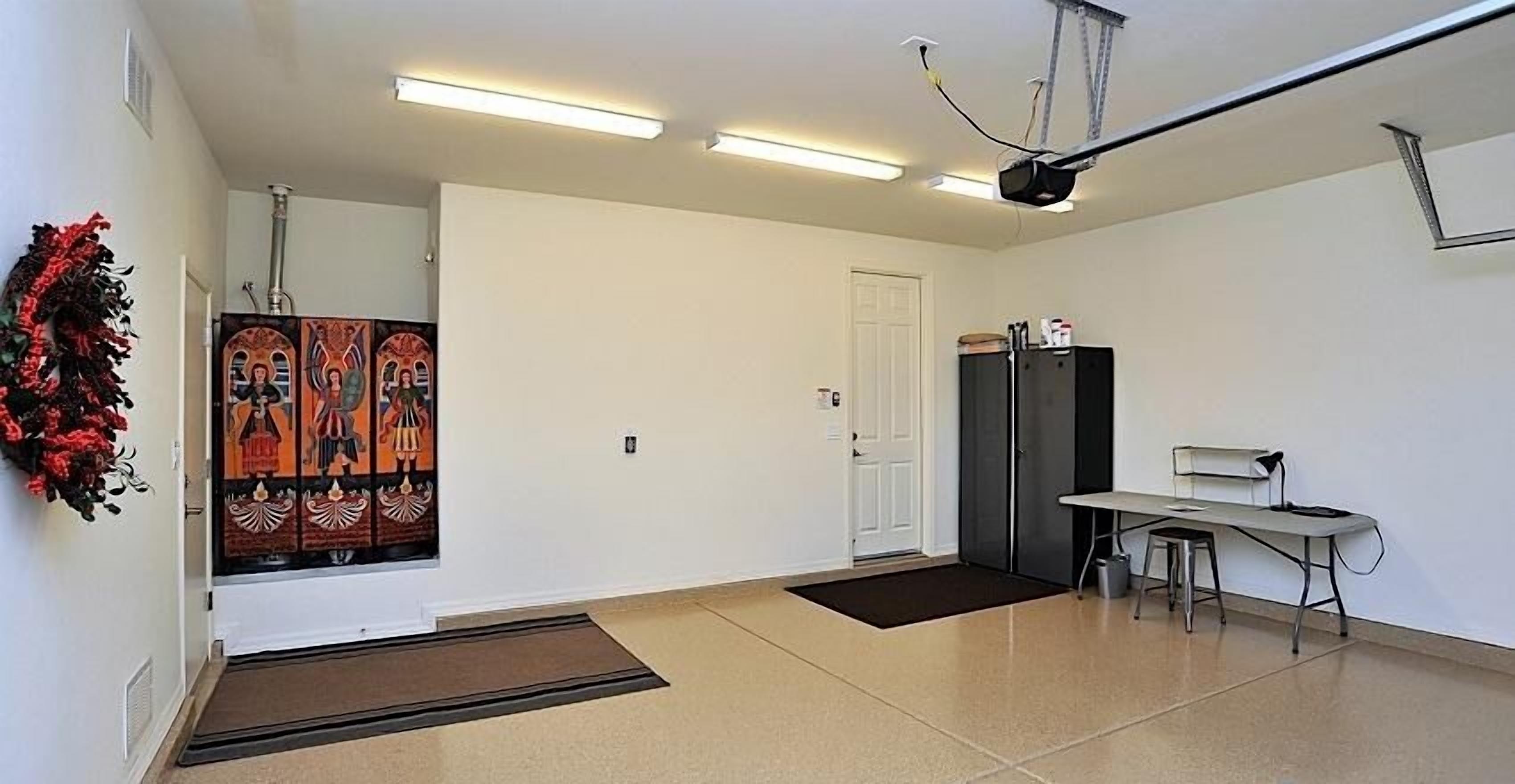 A room with a door, a black cabinet, a desk with a chair, and a wall-mounted projector.