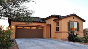 A single-story house with a brown garage, a small porch, and a landscaped front yard.