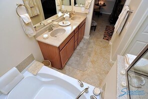 Un baño con tocador doble, bañera y un espejo grande.