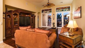 A spacious living room with a large entertainment center, a sofa set, and a dining area with a table and chairs. - Desert Falls By Signature Vacation Rentals (Glendale)
