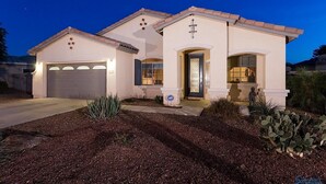 A two-story house with a garage, a front door, and a small porch area. - Desert Falls By Signature Vacation Rentals (Glendale)