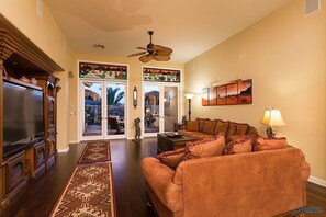 A living room with a large TV, a sofa, a coffee table, and a rug.