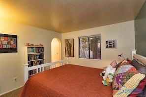 A bedroom with a large bed, a bookshelf, a window, and a door.