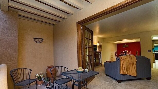 A living room with a sofa, a dining table with chairs, and a kitchen area in the background. - Casita Escriber By Signature Vacation Rentals (Oro Valley)