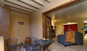 A living room with a sofa, a dining table with chairs, and a kitchen area in the background. - Casita Escriber By Signature Vacation Rentals (Oro Valley)