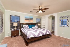 A bedroom with a bed, a nightstand, a ceiling fan, and a window with blinds.