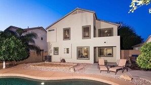 Une maison moderne à deux étages, dotée d’une piscine, d’un espace de détente extérieur et d’un jardin bien entretenu.