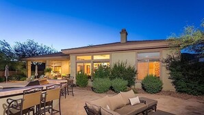 Ein modernes Haus mit Terrasse, Gartenmöbeln und einem gepflegten Garten.
