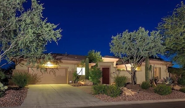 A residential house with a driveway, a garage, and a well-maintained garden with various plants and a cactus. - Caledonia Dreamin By Signature Vacation Rentals (Phoenix)