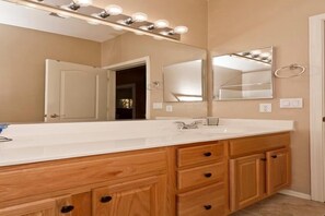 Un bagno con un ampio lavabo, uno specchio illuminato, mobili in legno e una porta.