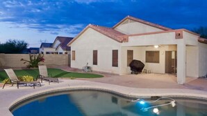 Uma casa moderna com piscina, área de churrasco e gramado bem cuidado.