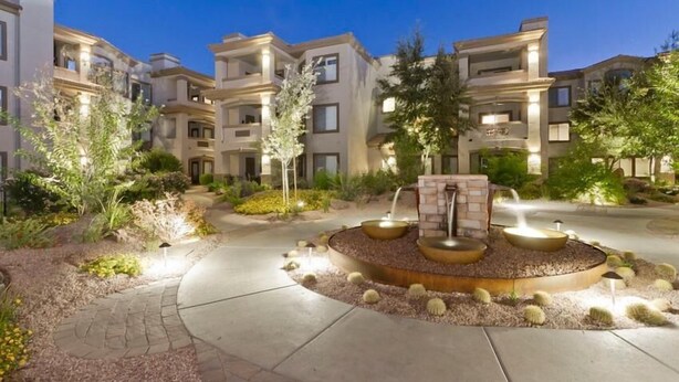 A landscaped courtyard with a central water feature, surrounded by multi-story residential buildings.