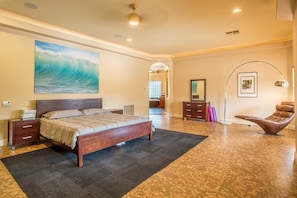 A bedroom with a bed, a nightstand, a dresser, a chair, a painting, and a hallway. - Bella Turquoise By Signature Vacation Rentals (Scottsdale)