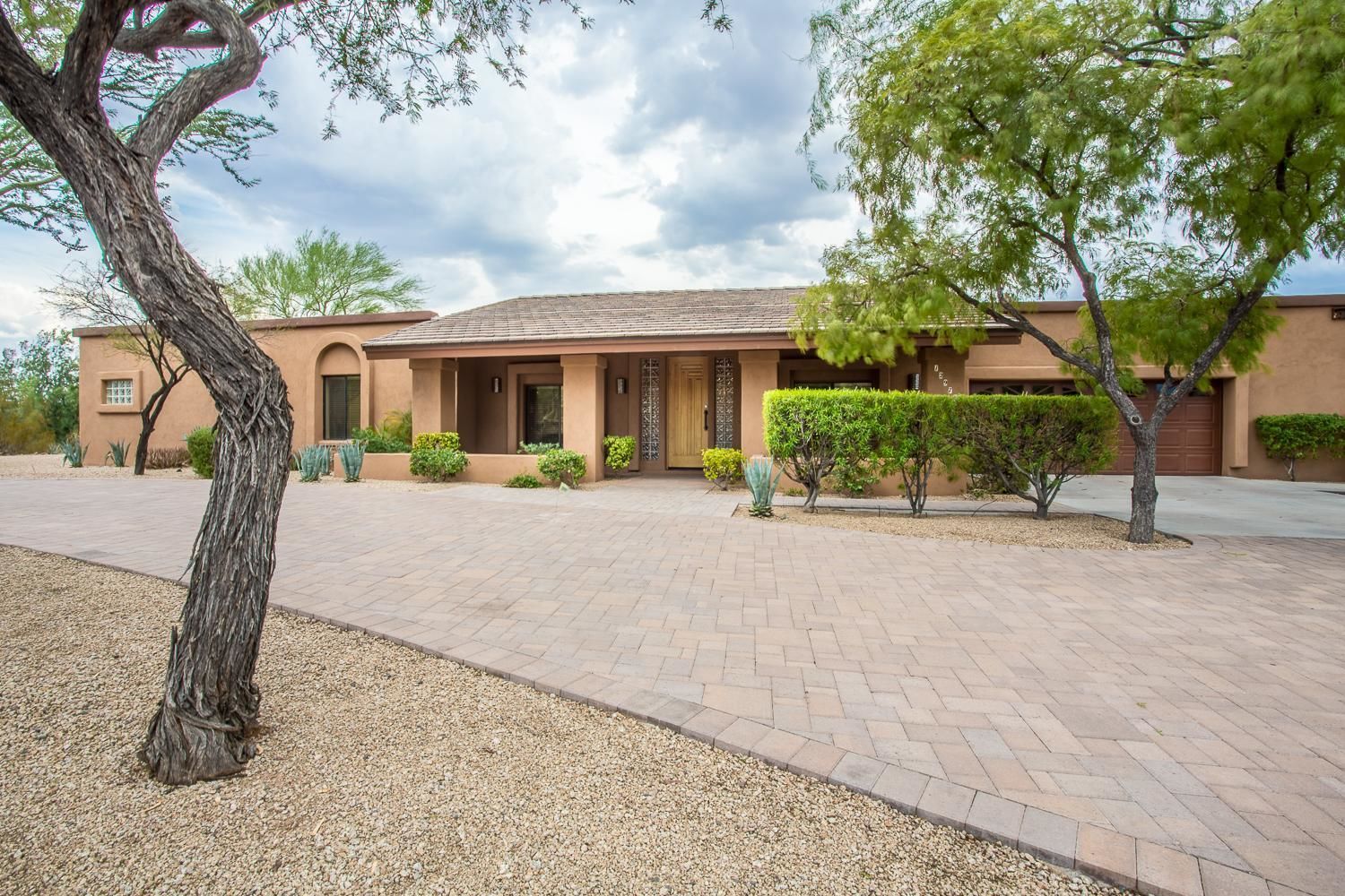 A building with a tiled roof, a paved driveway, and a well-maintained lawn.