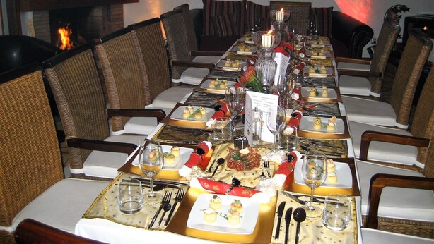 A long dining table set with multiple plates of food, glasses, and cutlery, surrounded by wicker chairs. - Birdcage Gay Resort - Adult Only (San Bartolomé de Tirajana)