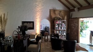 Un salon chaleureux avec une cheminée, une bibliothèque et un coin repas comprenant une table et des chaises.