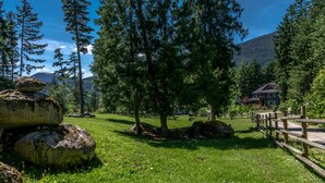 A serene outdoor area with a wooden fence, large rocks, and a house in the background. - The Cabin at Sweetwater Lane Farm (Mount Currie)