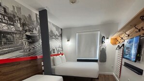 A compact hotel room with a bed, a small desk, and a TV mounted on the wall. - Hotel 1080 Brooklyn (Brooklyn)