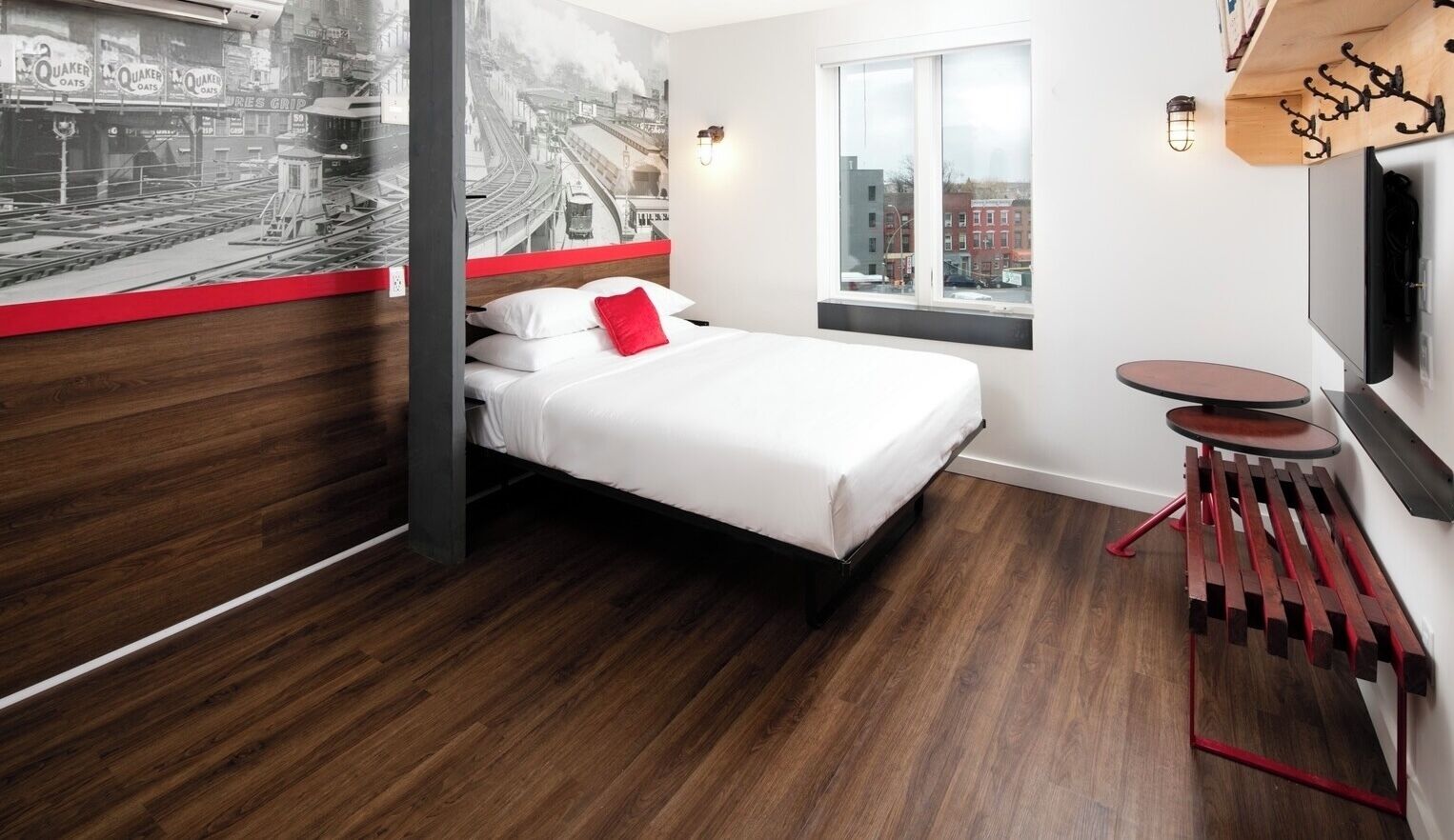 A modern hotel room with a bed, a small table, and a window with a city view.
