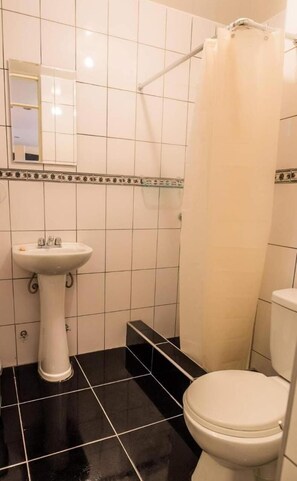 A bathroom with a white sink, black tiled floor, a white toilet, and a shower curtain.