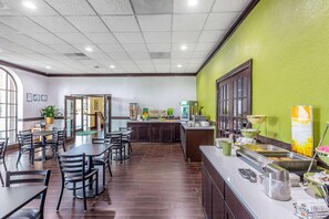 Un restaurante con comedor, cocina y una barra para buffet.