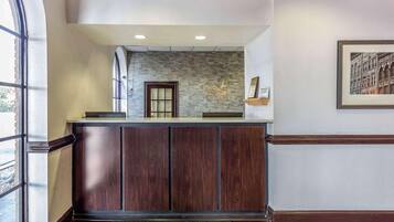 A hotel reception area with a stone wall, a reception desk, and a framed picture on the wall.