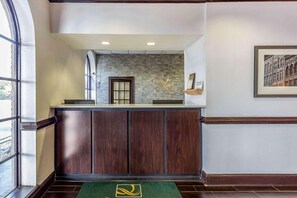Zona de recepción de un hotel con pared de piedra, un mostrador de recepción y un cuadro enmarcado en la pared.