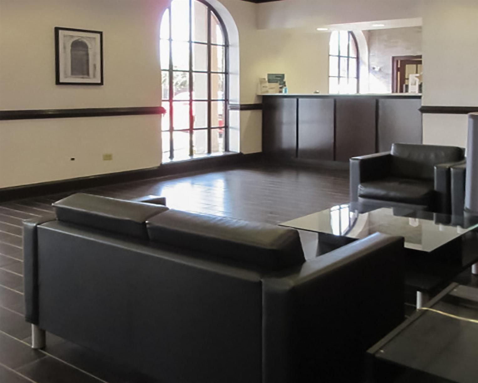 Un vestíbulo moderno con un sofá de cuero negro, una mesa de centro de vidrio y un sillón de cuero negro.