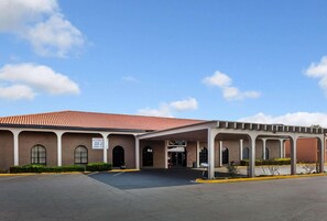 Un edificio con tejado de tejas rojas, ventanas arqueadas y un área de entrada cubierta.