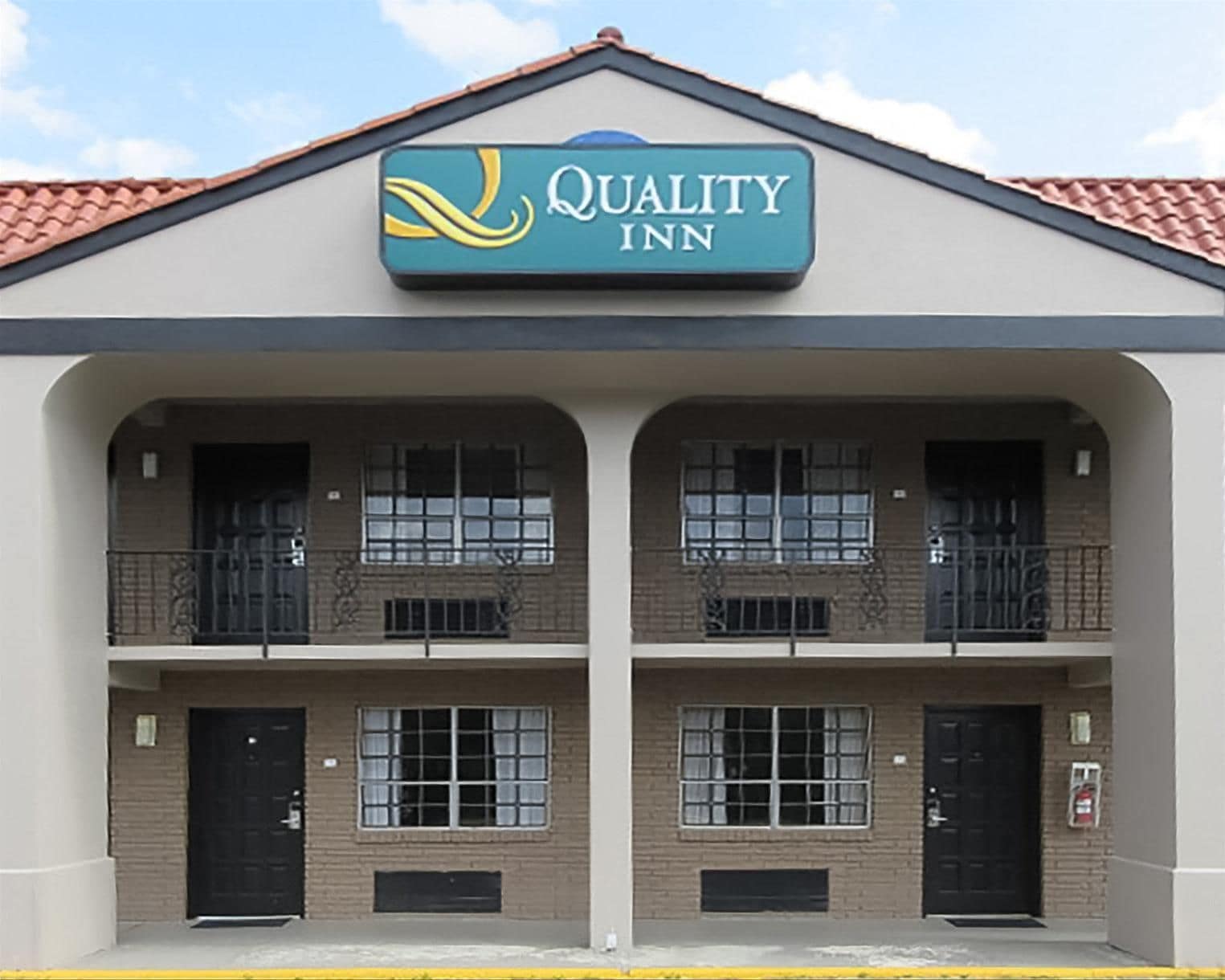 Un bâtiment à deux étages, avec une enseigne indiquant « Quality Inn » au-dessus de l’entrée.