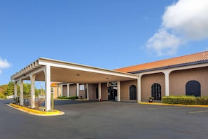 Un hotel con entrada cubierta, fachada de ladrillo y cielo azul despejado.