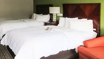 Una habitación de hotel con dos camas, una mesita de noche con una lámpara y una silla roja.