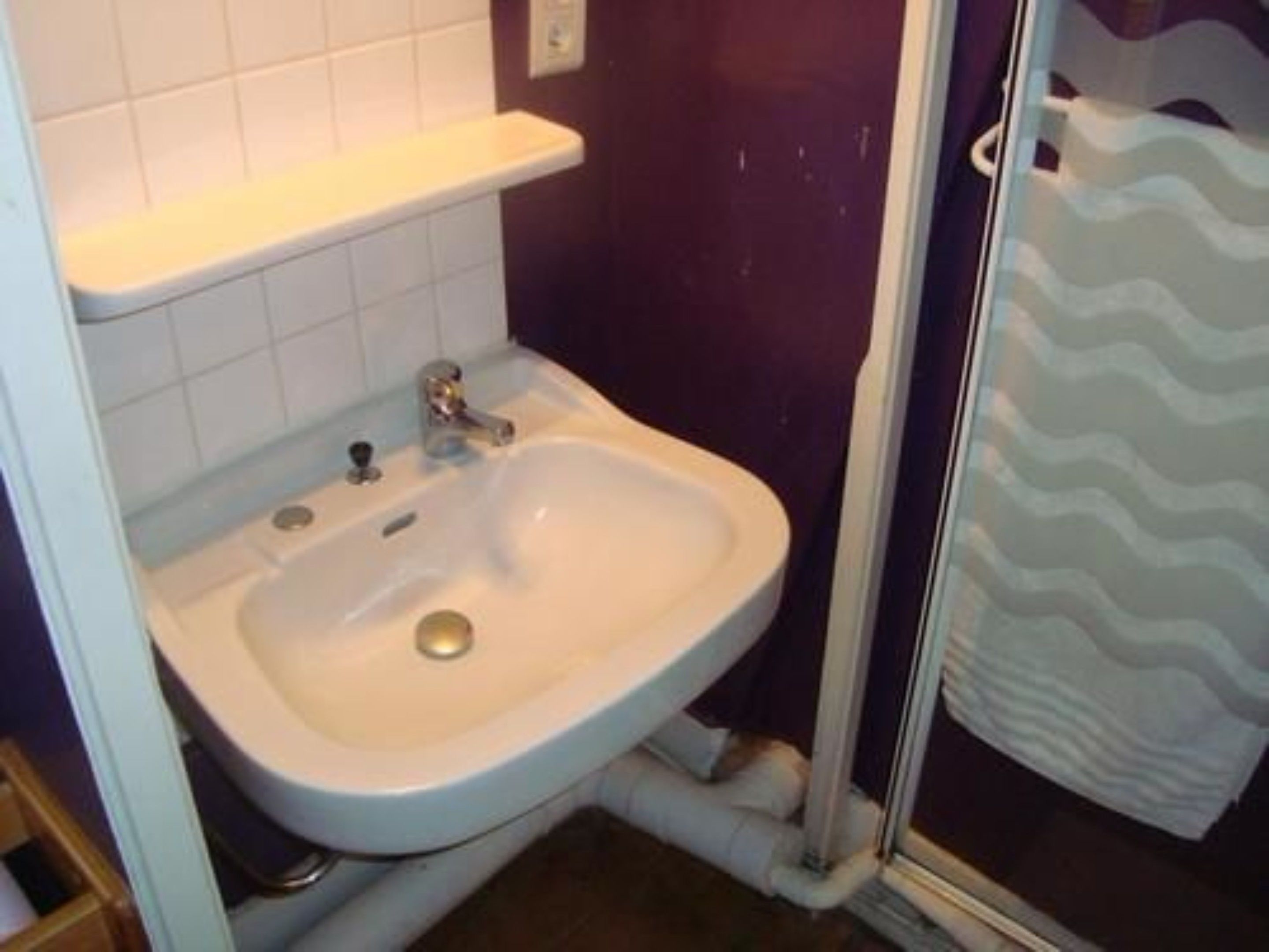A bathroom with a white sink, a mirror, and a shower area.