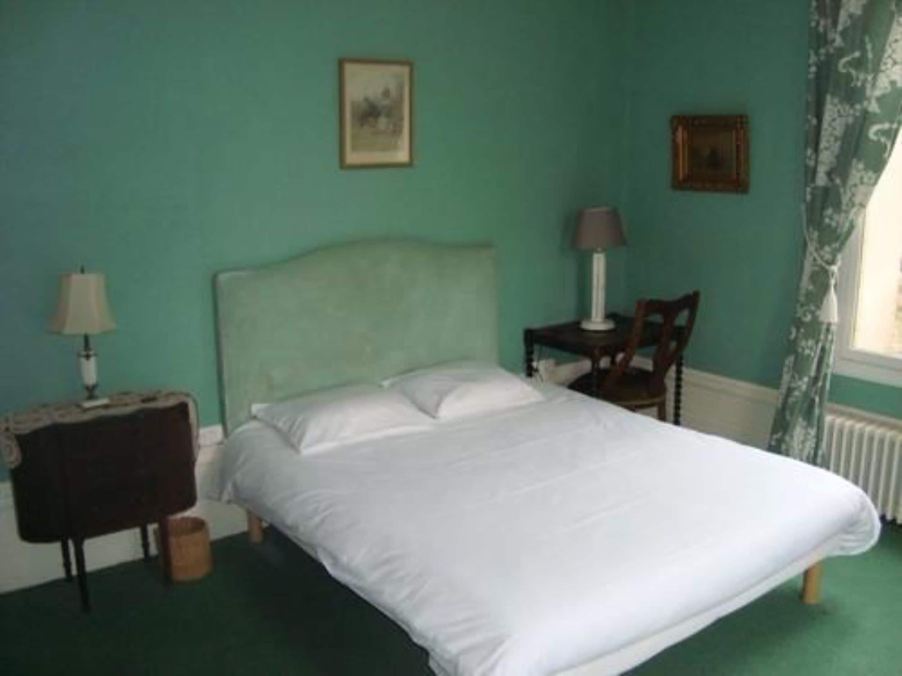 A bedroom with a bed, a nightstand, a chair, and two wall-mounted lamps.