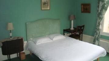 A bedroom with a bed, a nightstand, a chair, and two wall-mounted lamps.